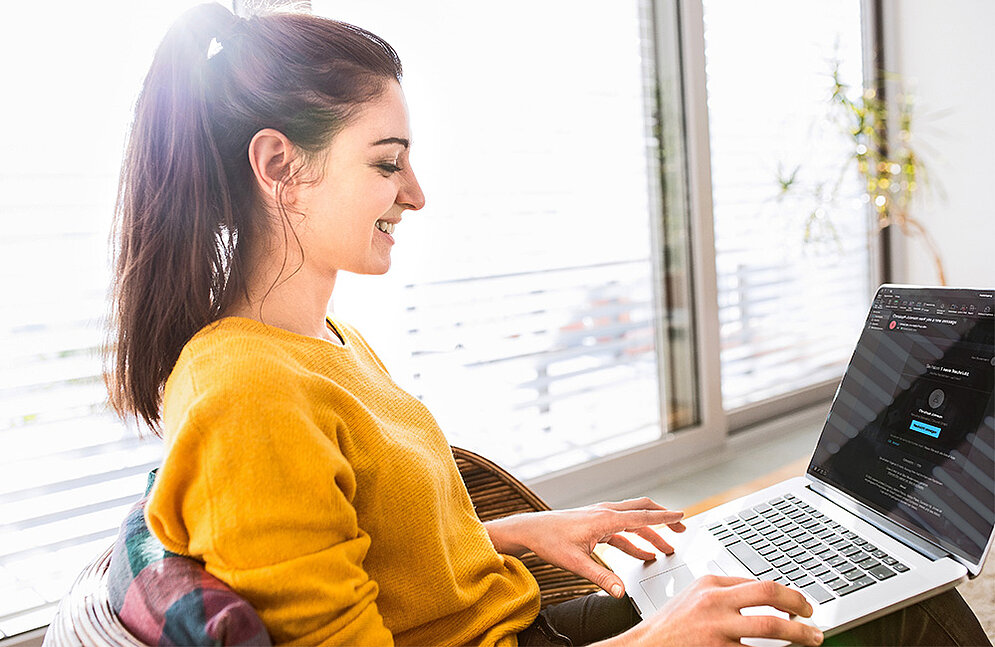 Une simulation de phishing renforce la sensibilisation à la sécurité Femme heureuse avec un ordinateur portable sur les genoux